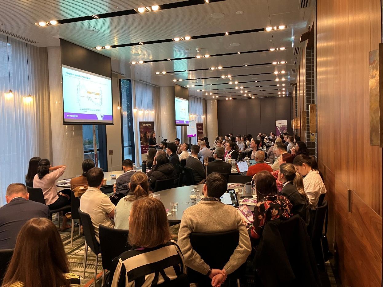 Clinicians seated in a conference room during a PD Academy 2026 presentation, with presentation screens visible at the front of the room.