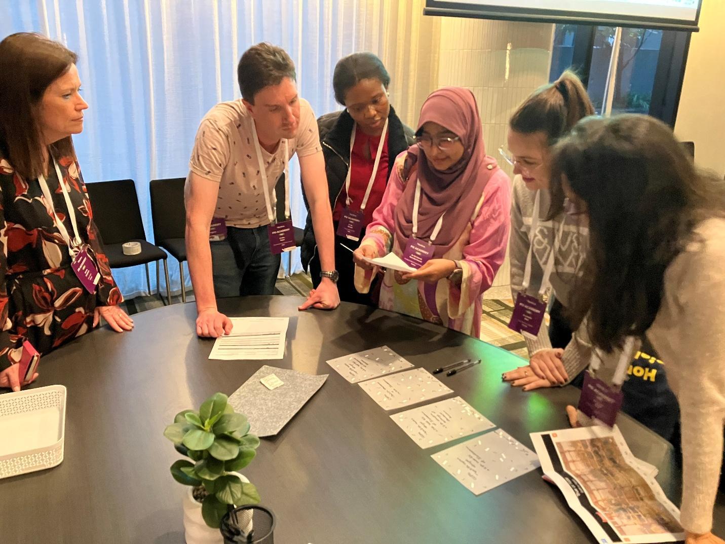 Six PD Academy participants gathered around a table, working together on an interactive clinical problem-solving activity.