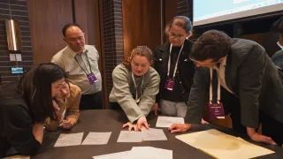 Group of people leaning around a table looking at paperwork