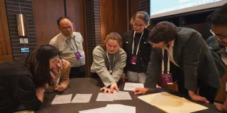 Group of people leaning around a table looking at paperwork