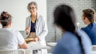 A woman in a lab coat engaging with her audience during a discussion