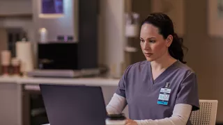 Healthcare professional sitting at table on laptop