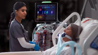 A clinician uses the PrisMax system at a patient's bedside