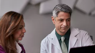 Two clinicians look at data on a desktop computer.