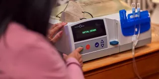 A woman interacts with the Homechoice Claria on her bedside table.