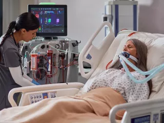 A clinician uses the PrisMax system at the patient bedside