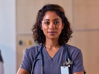 Smiling healthcare professional stands with her arms crossed