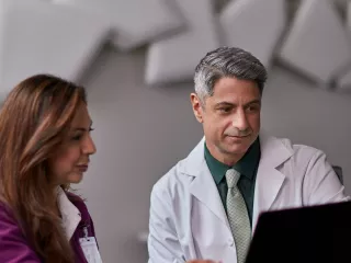 Two clinicians look at data on a desktop computer.