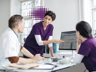 Healthcare professionals discuss data on a desktop device